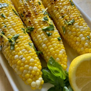 Cast iron corn on the cob with herb butter on a plate.