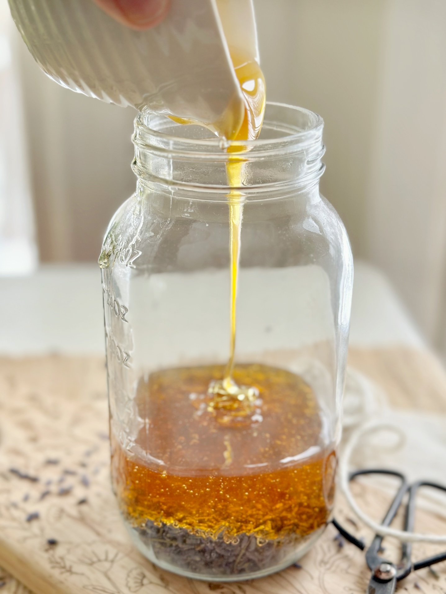 Pouring the honey over the lavender in the jar.