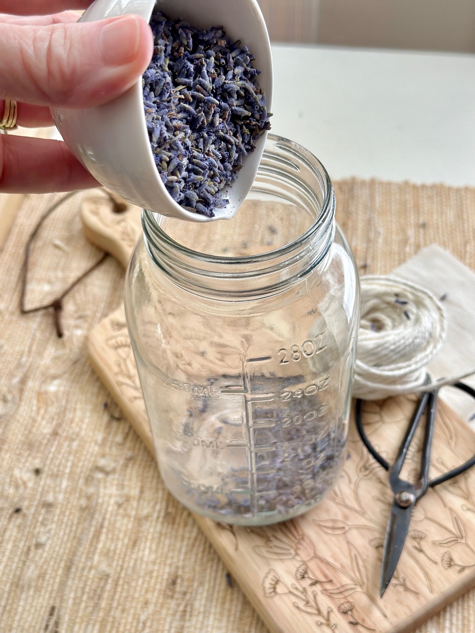 Adding lavender to a clean glass jar for lavender honey.