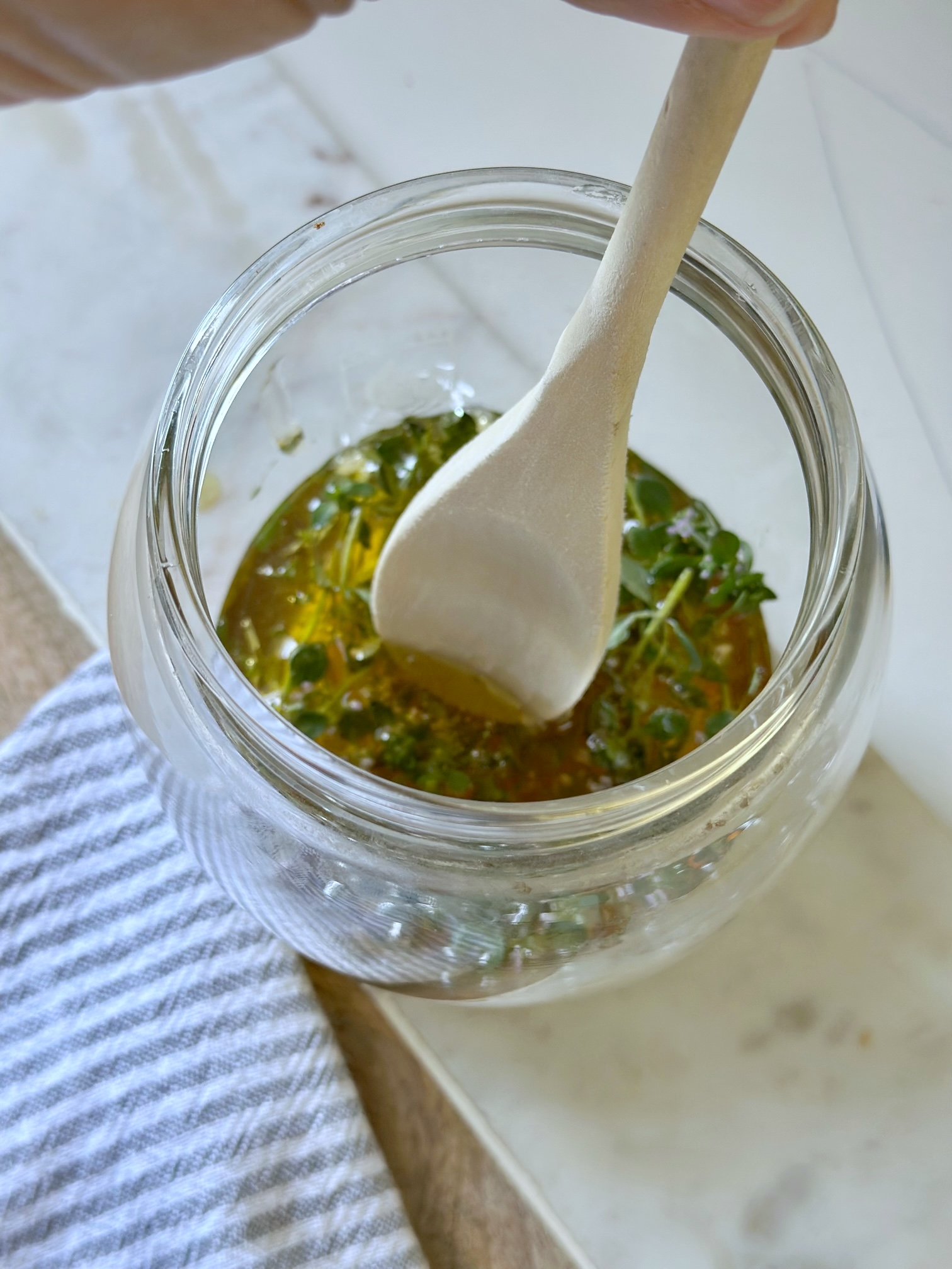 Using a wooden spoon stirring the thyme honey mixture.