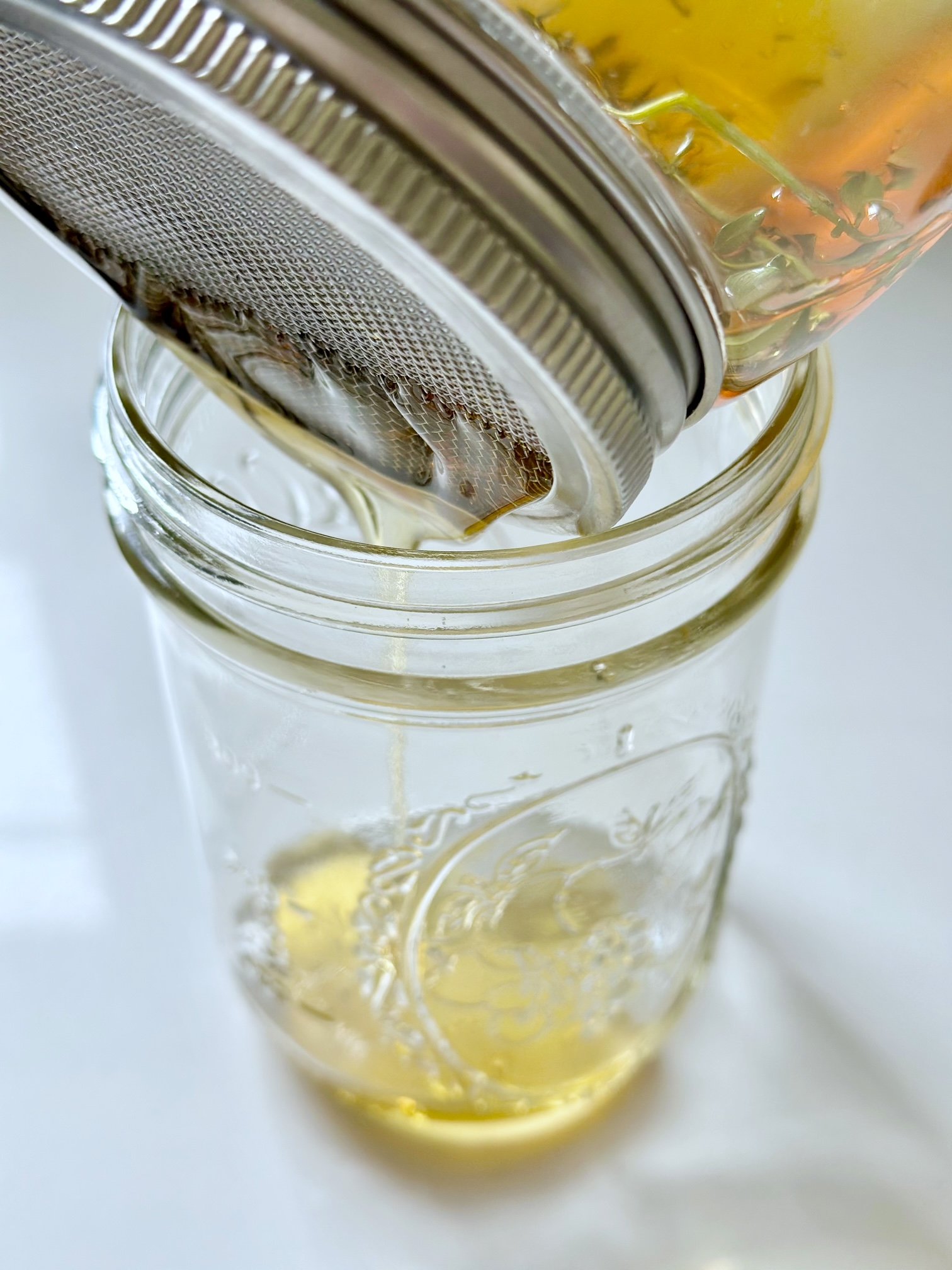 Straining thyme honey into a jar.