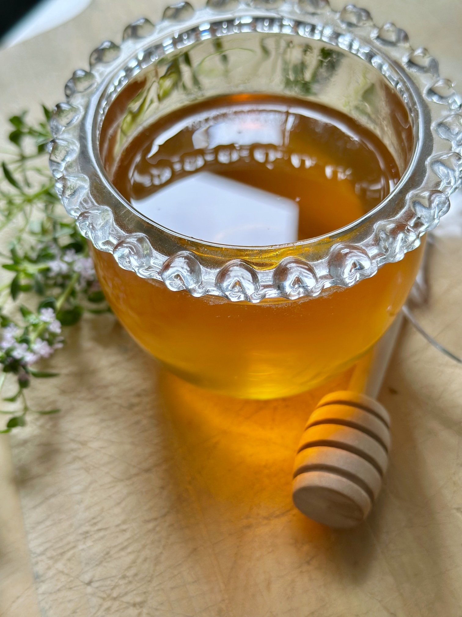 Thyme honey in a clear glass honey jar.